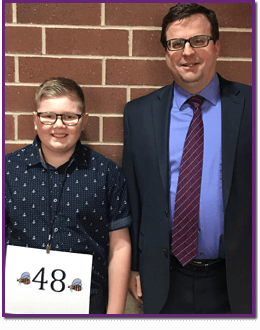 Adult standing with a spelling bee contestant