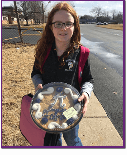 Student holding a large cookie with the Pi math symbol on it
